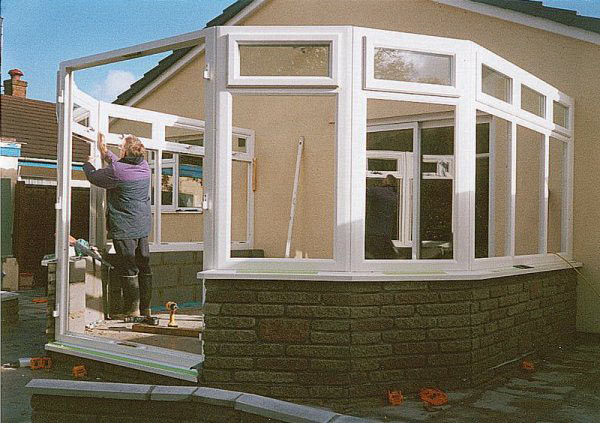 White conservatory frame being put up on a brick base