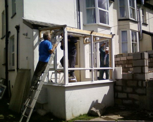 An extension under construction with builders working from ladders