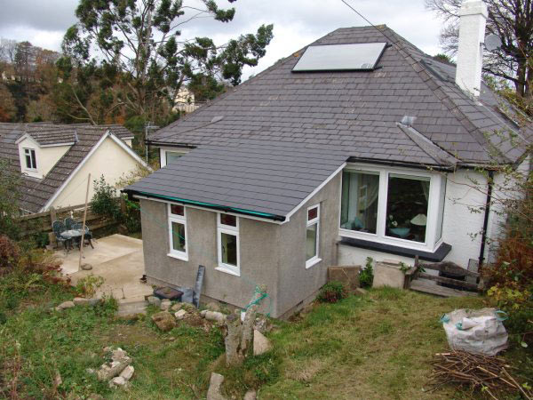 Rendered extension on a bungalow with a hipped slate roof and a solar panel