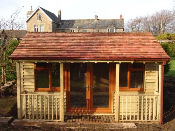 Front of a timber garden room with a veranda and cedar shingle roof