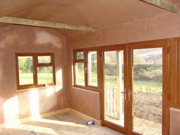 Plastered interior of a garden room with french doors open onto the garden