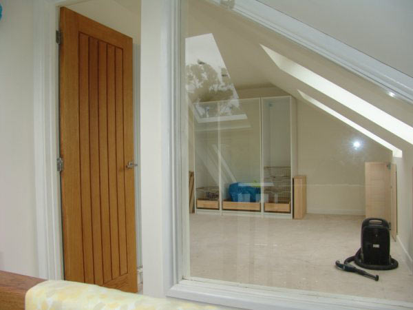 A finished loft room with an oak door and a roof window