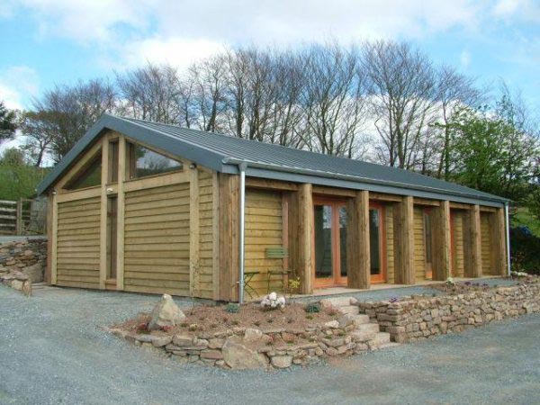 Long timber-clad studio with glazed doors set behind a stone retaining wall